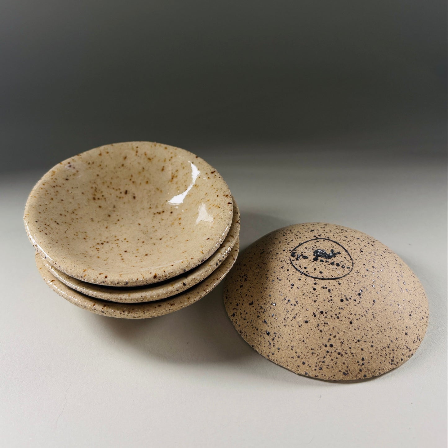 Set of ceramic bowls with speckled texture on a neutral background